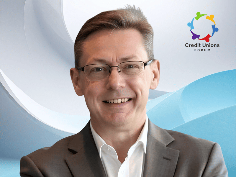 Greg Cook smiling in a gray blazer in front of a blue graphic backdrop with the Credit Unions Forum logo